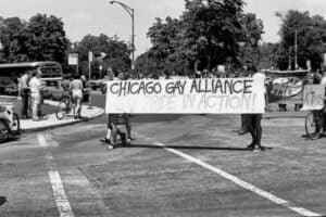 Chicago Gay Alliance protest march with rainbow banner at Pride parade, advocating LGBTQ+ rights and inclusion.