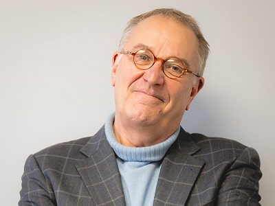Inspirational author and yarn enthusiast smiling confidently in a plaid blazer.