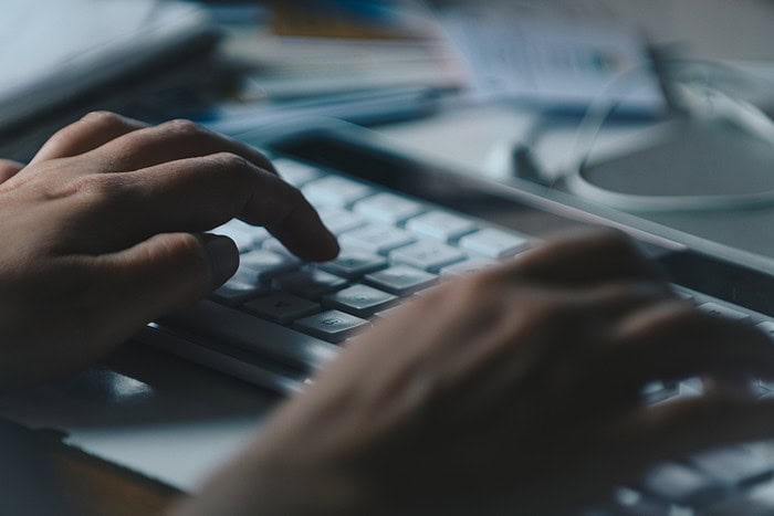 Close up of hands using a keyboard.