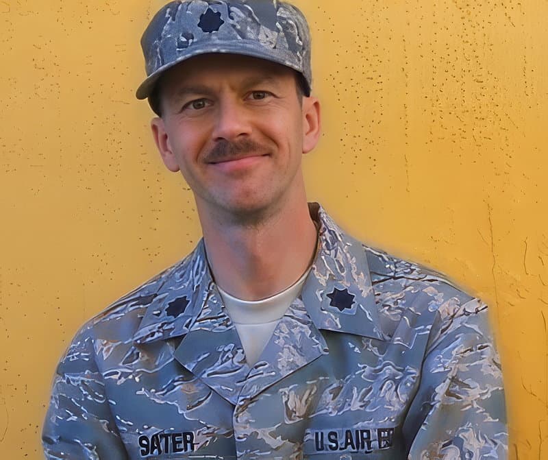 Photograph of author Richard C. Sater in US Air Force fatigues, posed against a yellow wall.