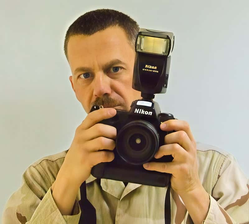 Photograph of author Ricard C. Sater wearing US Air Force fatigues, who was a military photojournalist, posed with his camera.