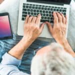 Senior person using laptop and smartphone.